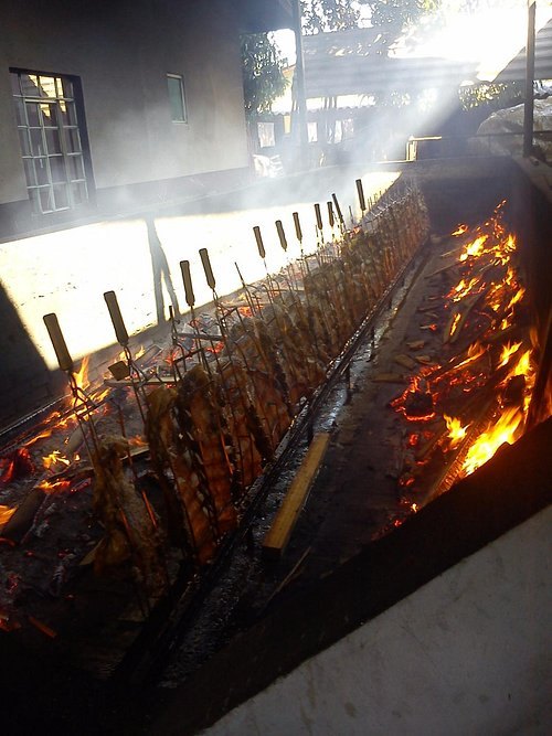 Costelas nos espetos sobre as brasas, na churrasqueira de fogo de chão